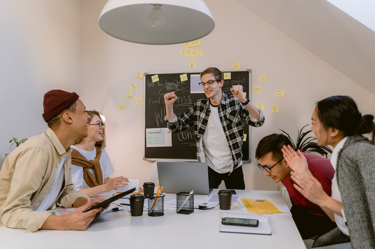Diverse group of young professionals celebrating in a modern office setting.